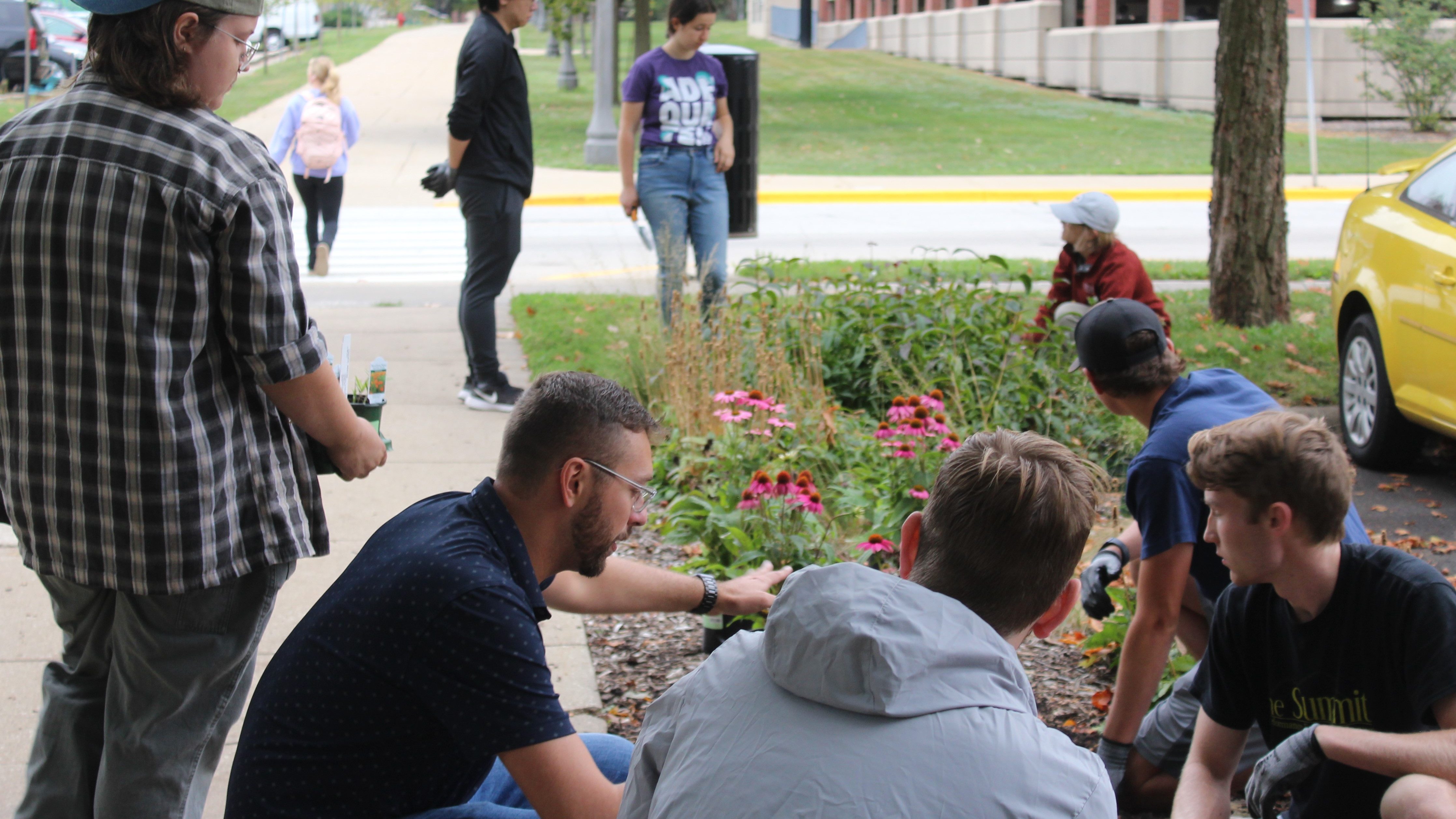 Students volunteering by planting at the Red Oak Rain Garden learning from staff.