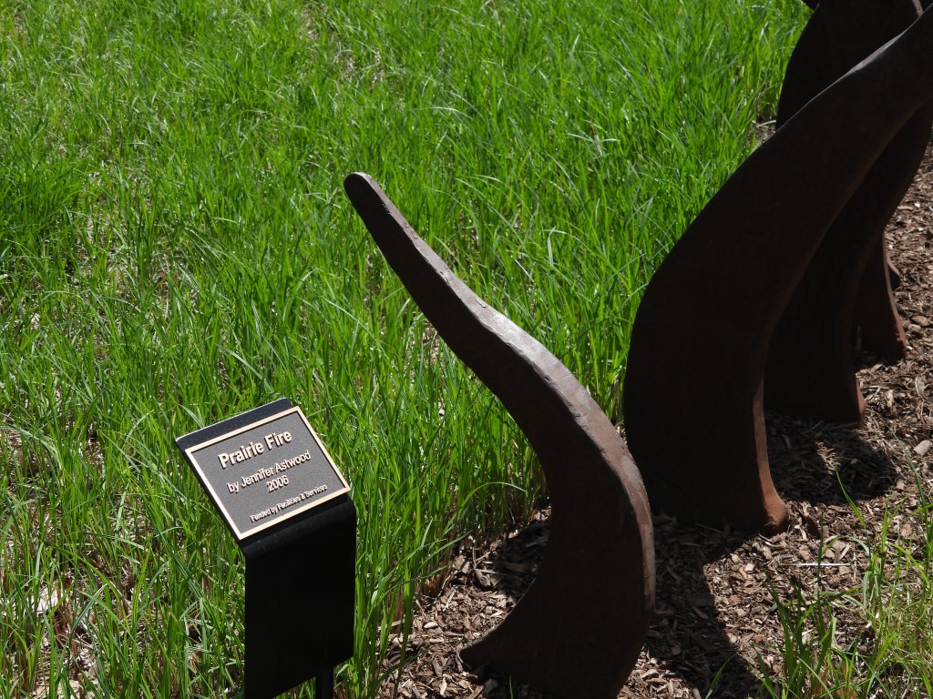 A sculpture identification plaque reads "Prairie Fire by Jennifer Astwood, 2006, Funded by Facilities & Services"